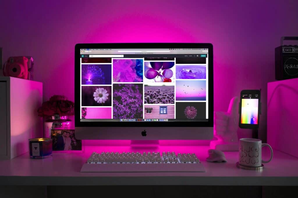 Current image: Modern desk setup with neon lighting and a desktop computer displaying colorful images.